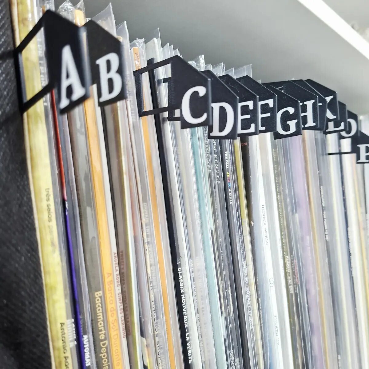 Divisórias alfabéticas pretas organizando discos de vinil na estante de um cliente
