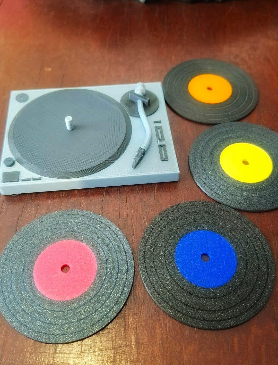 Porta-copos de disco de vinil coloridos com mini toca-discos sobre a mesa